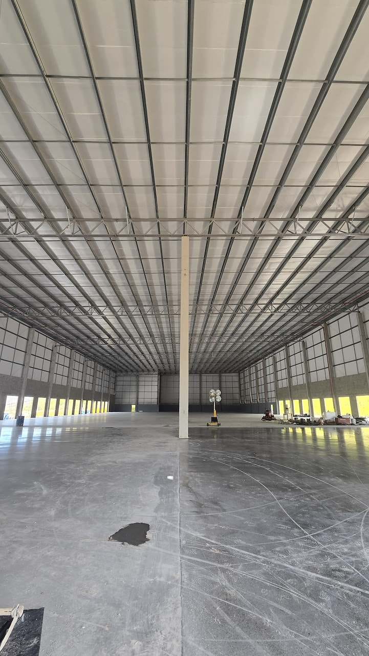 Interior de galpão industrial com estrutura metálica e piso de concreto polido